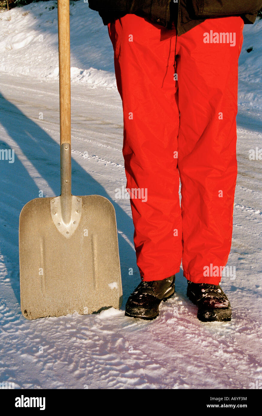 Mann steht neben einer Schaufel im Schnee Stockfoto