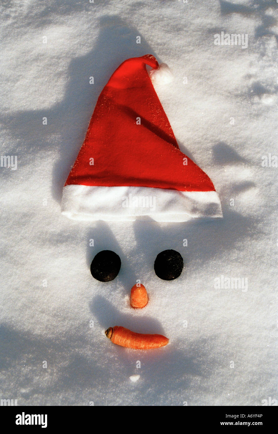 Schneemann s Gesicht mit einer Weihnachtsmütze im Schnee Stockfoto