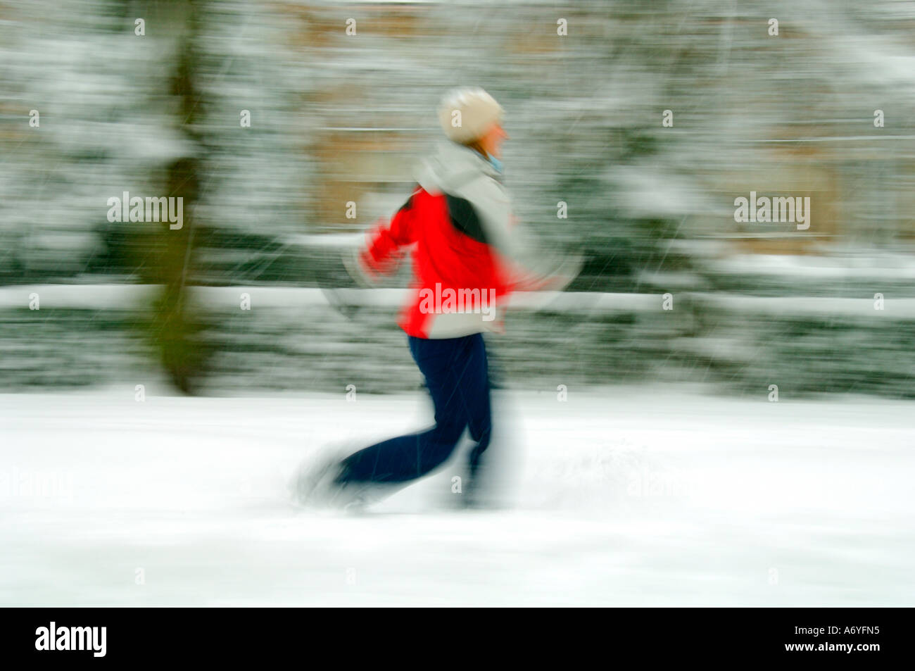 Frau mit roter Jacke Wandern in starkem Schneefall Stockfoto