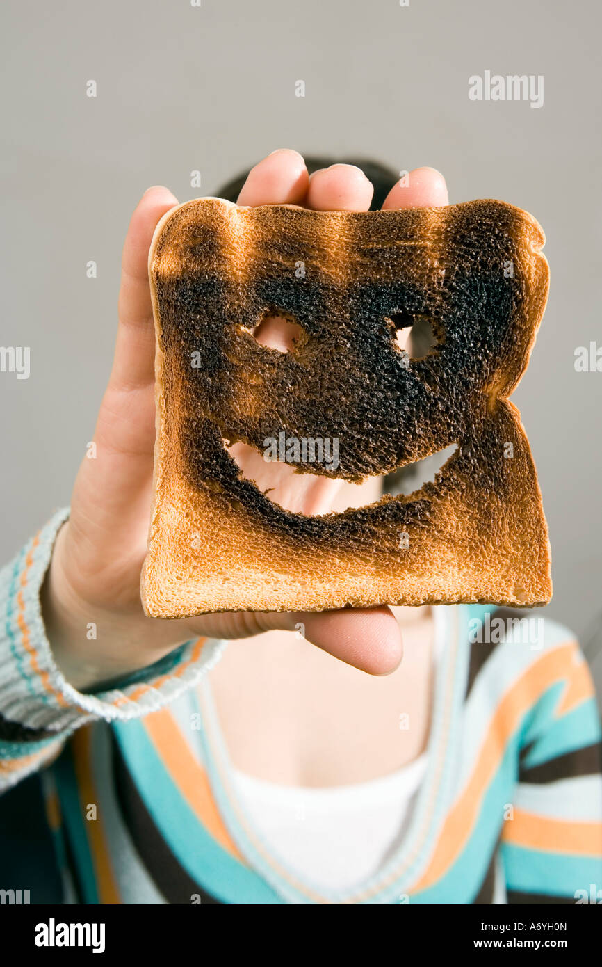 Frau mit verbranntem Toast vor Gesicht Stockfoto