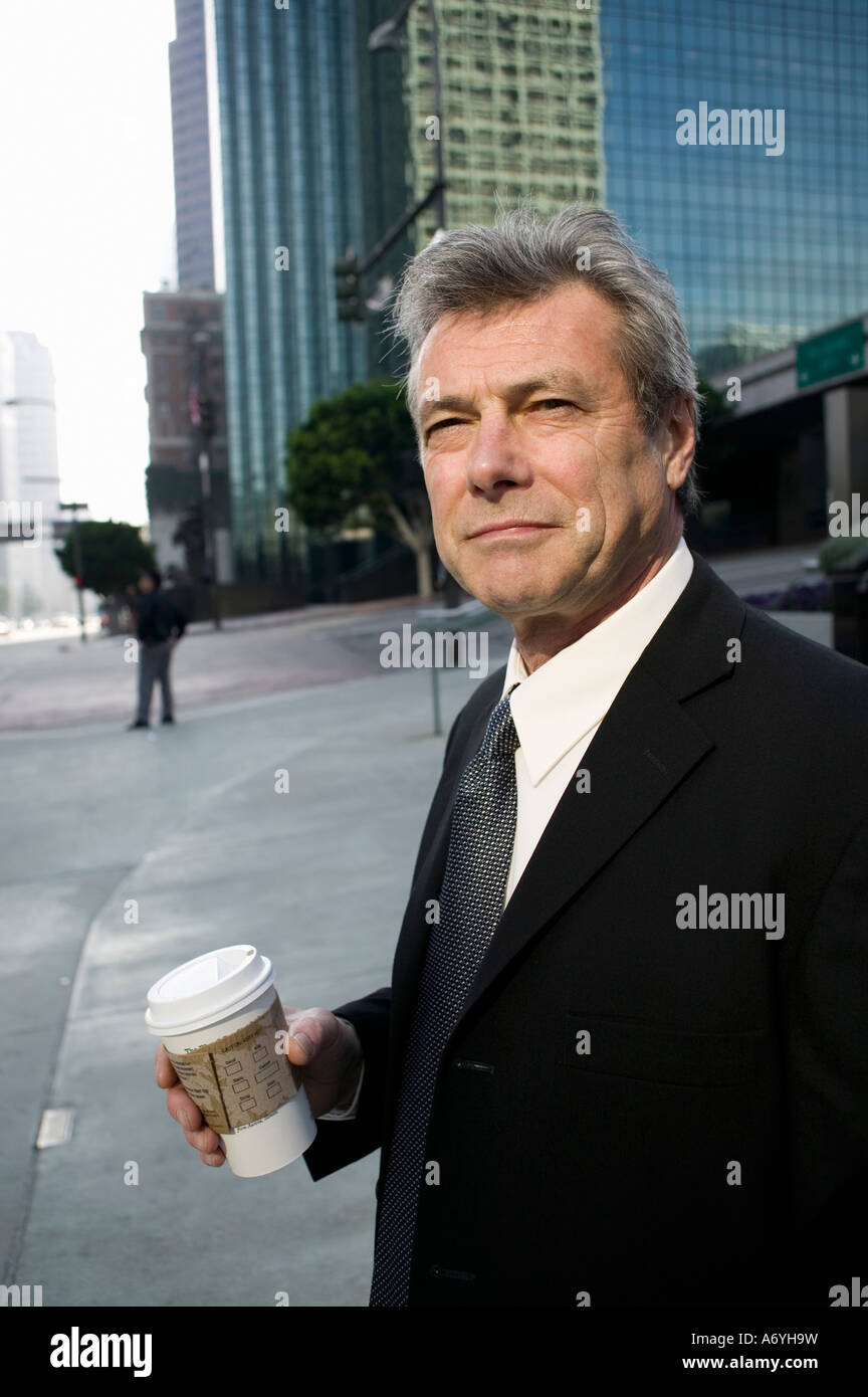 Geschäftsmann stand an einer Straßenecke hält eine Tasse Kaffee Stockfoto