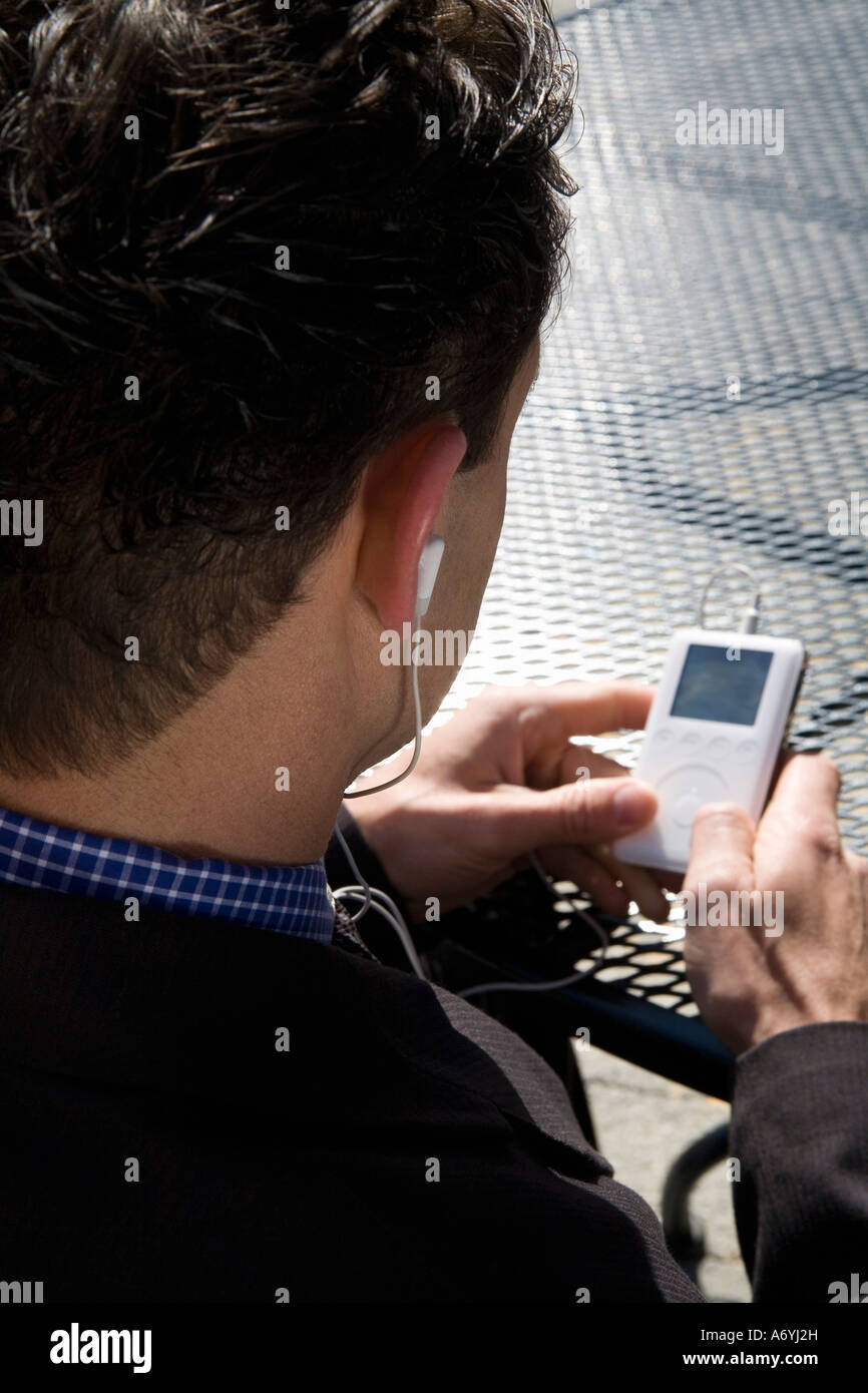 Geschäftsmann, sitzen in einem Straßencafé einen MP3-Player anhören Stockfoto