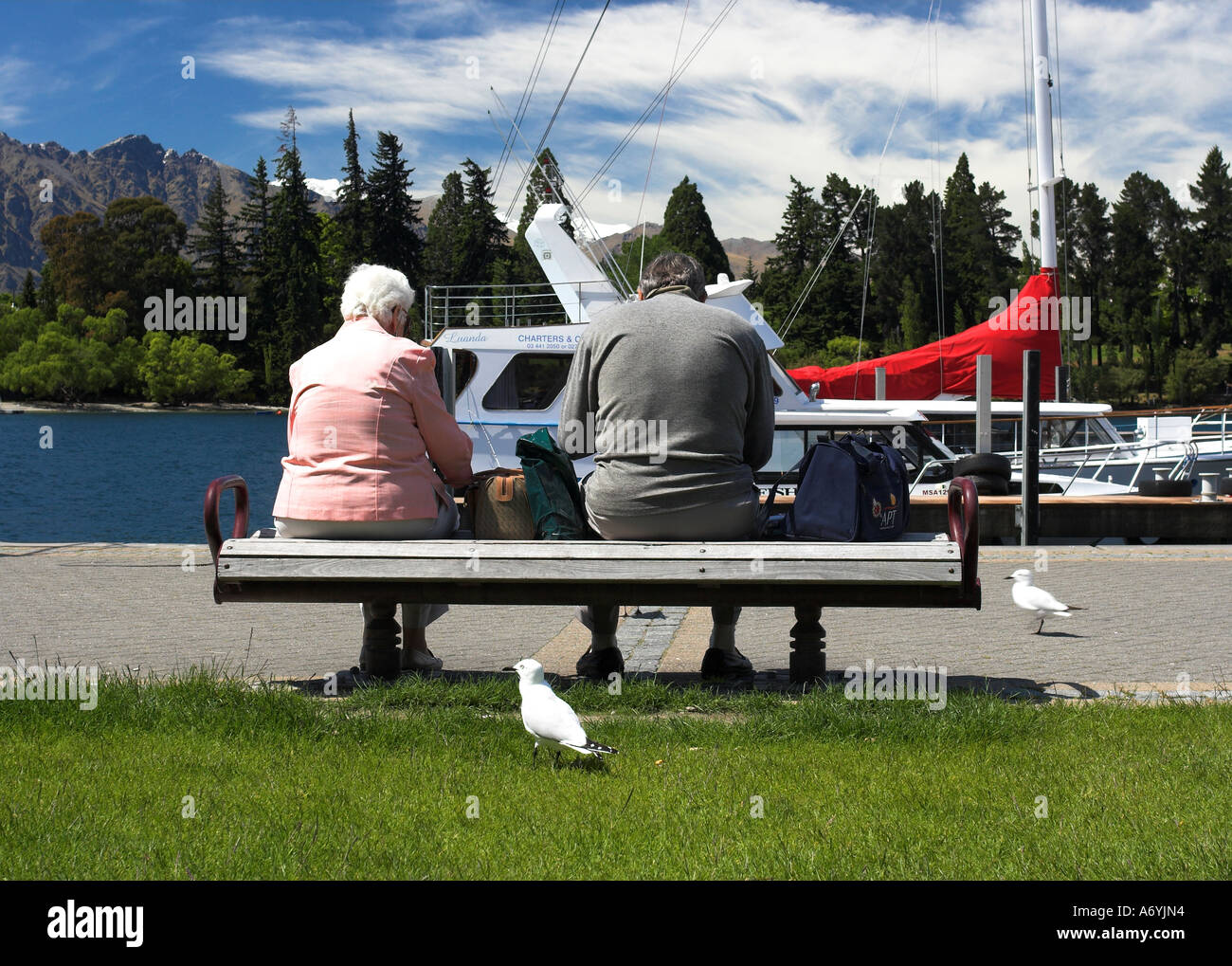 Ein altes Ehepaar sitzt auf einer Bank See in Queenstown, Neuseeland. Stockfoto