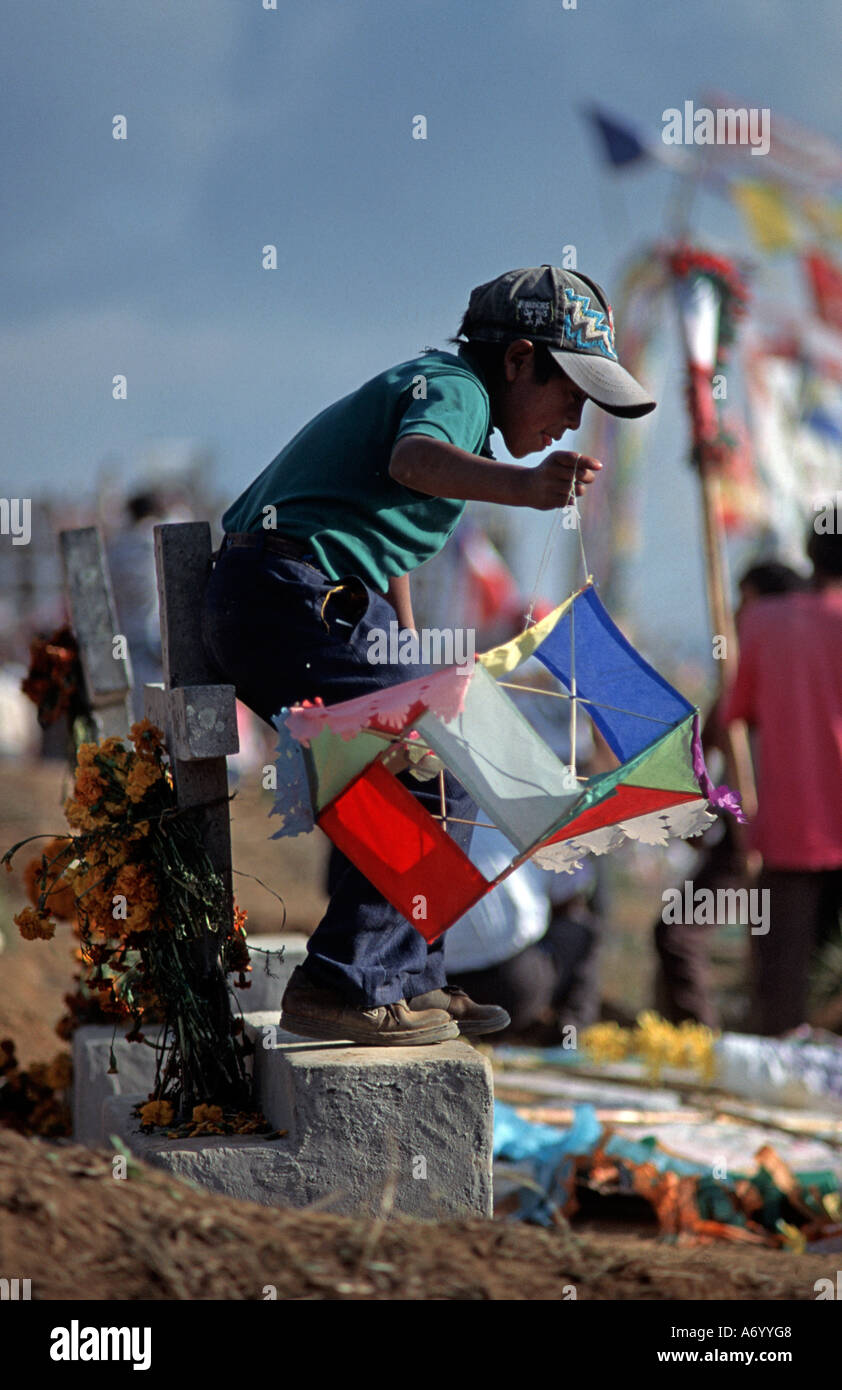 Junge mit bunten Papier-Drachen stehend auf einem Grabstein 1 November feiern in Santiago Sacatepequez GUATEMALA Stockfoto