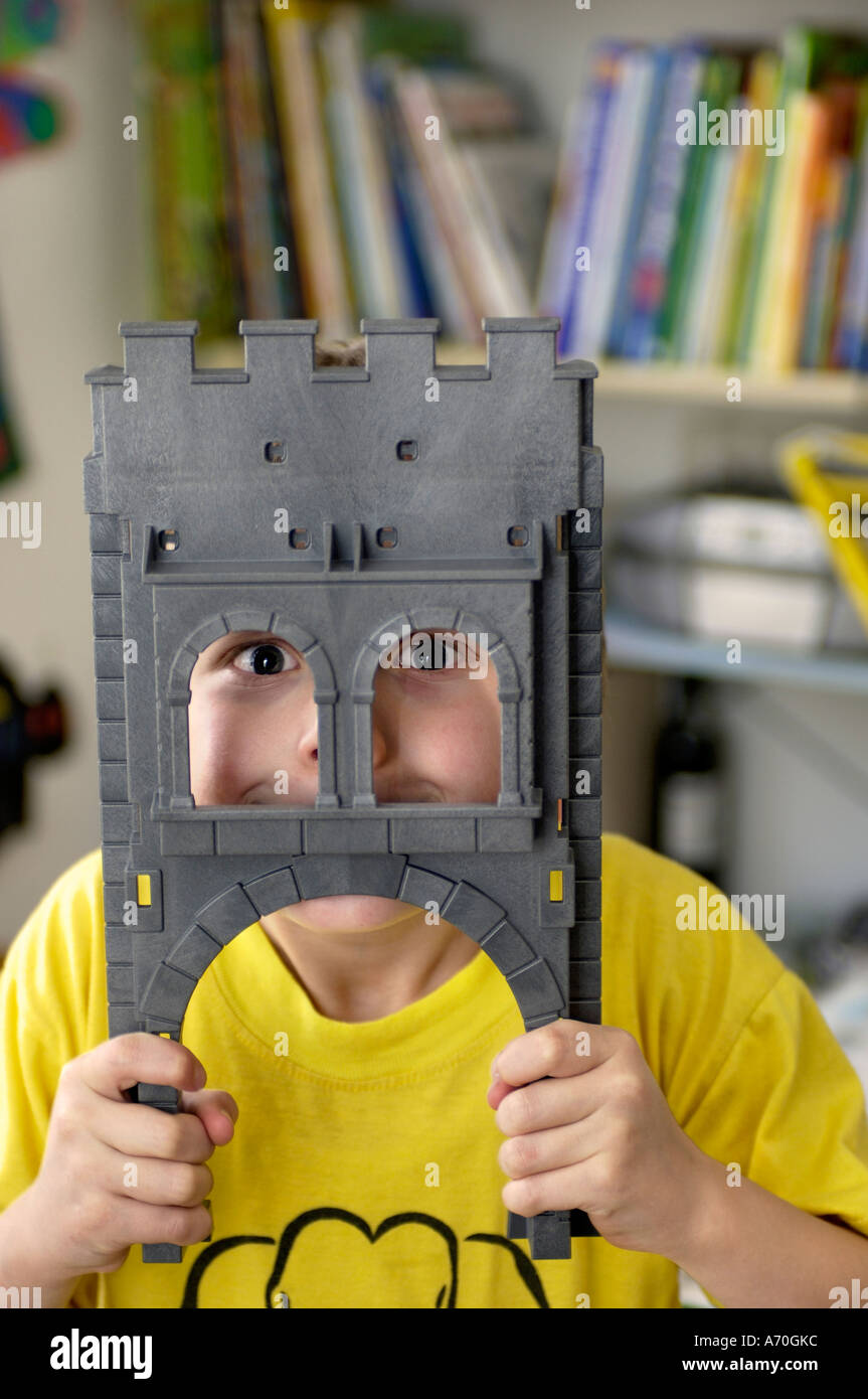 Lustige sieben Jahre alter Junge Blick durch das Tor von seinem Spielzeug Ritterburg Stockfoto