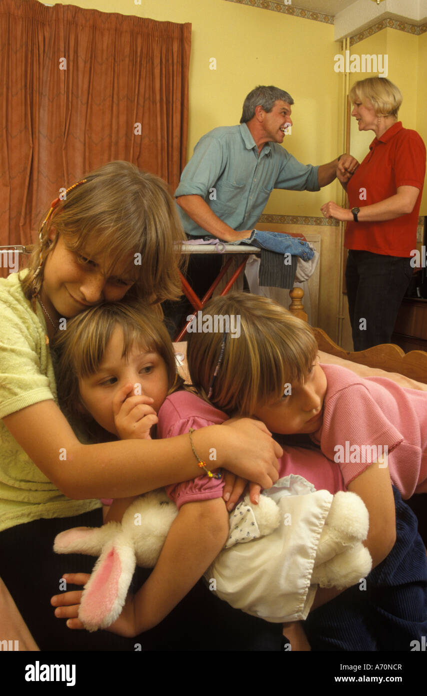 3 Kinder, die miteinander kuscheln, während die Eltern streiten Stockfoto