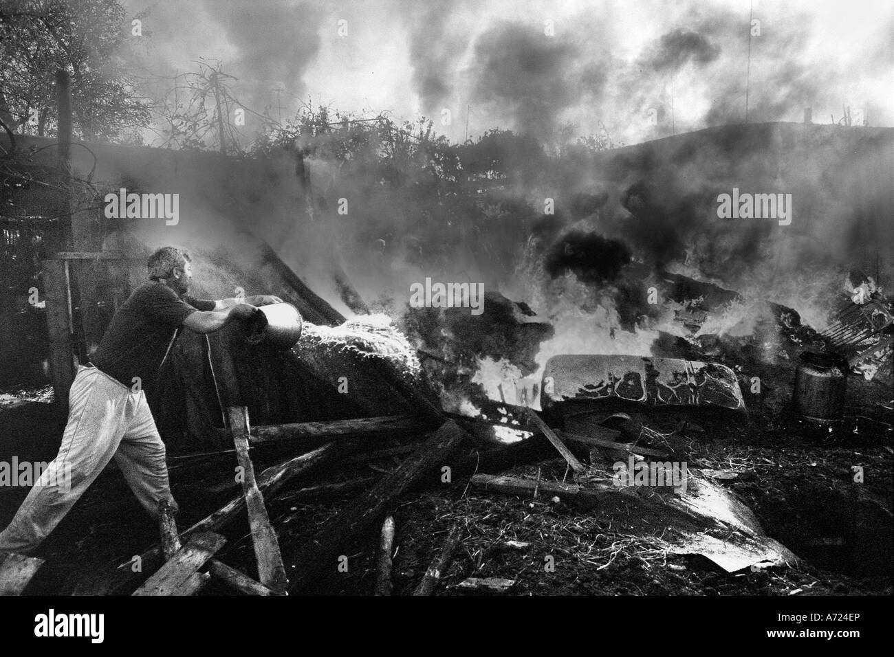 Ein Mann versucht, die Überreste von seinem Haus brennen zu beenden Stockfoto