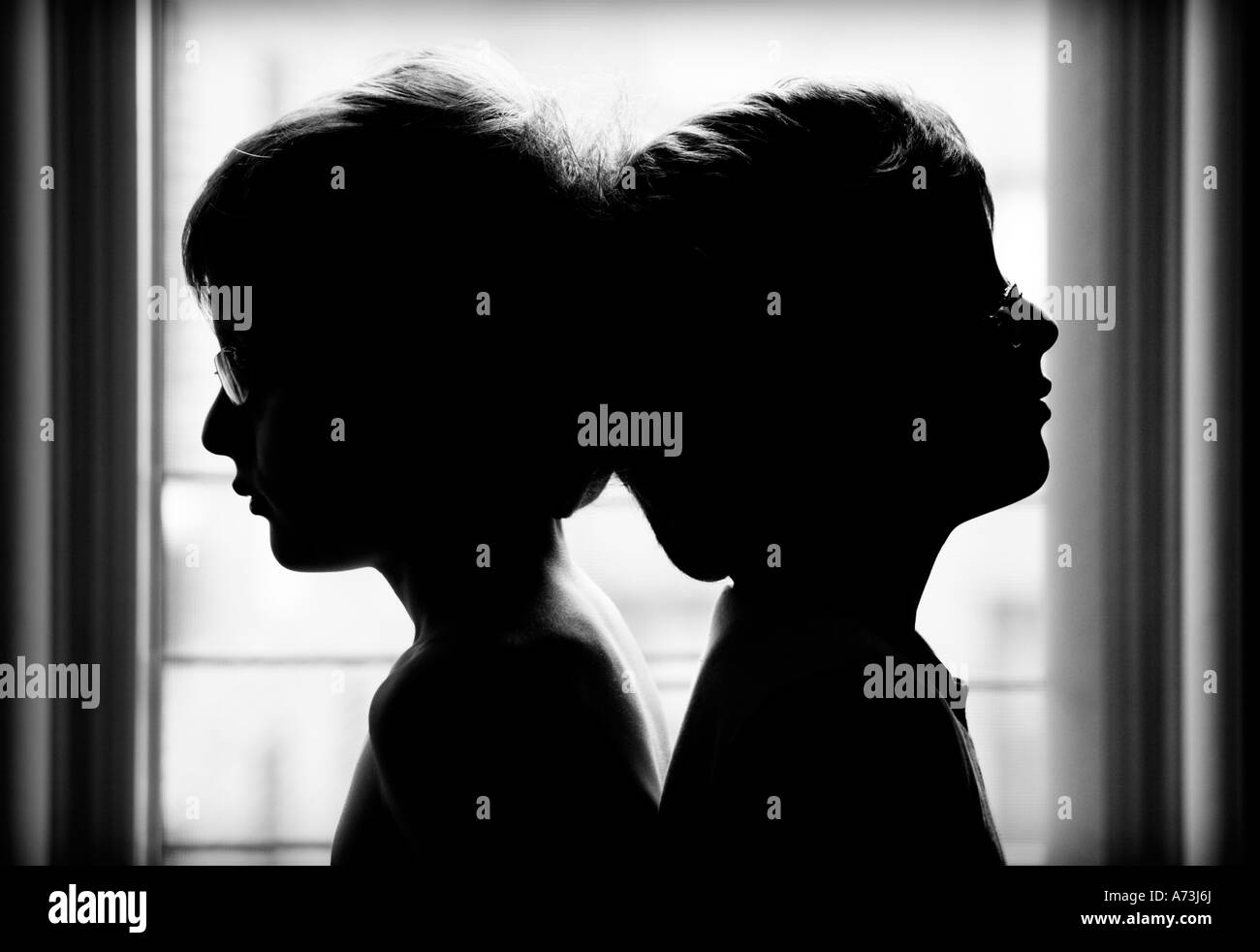 zwei jungen tragen Gläser Rücken an Rücken Silhouetten Stockfoto
