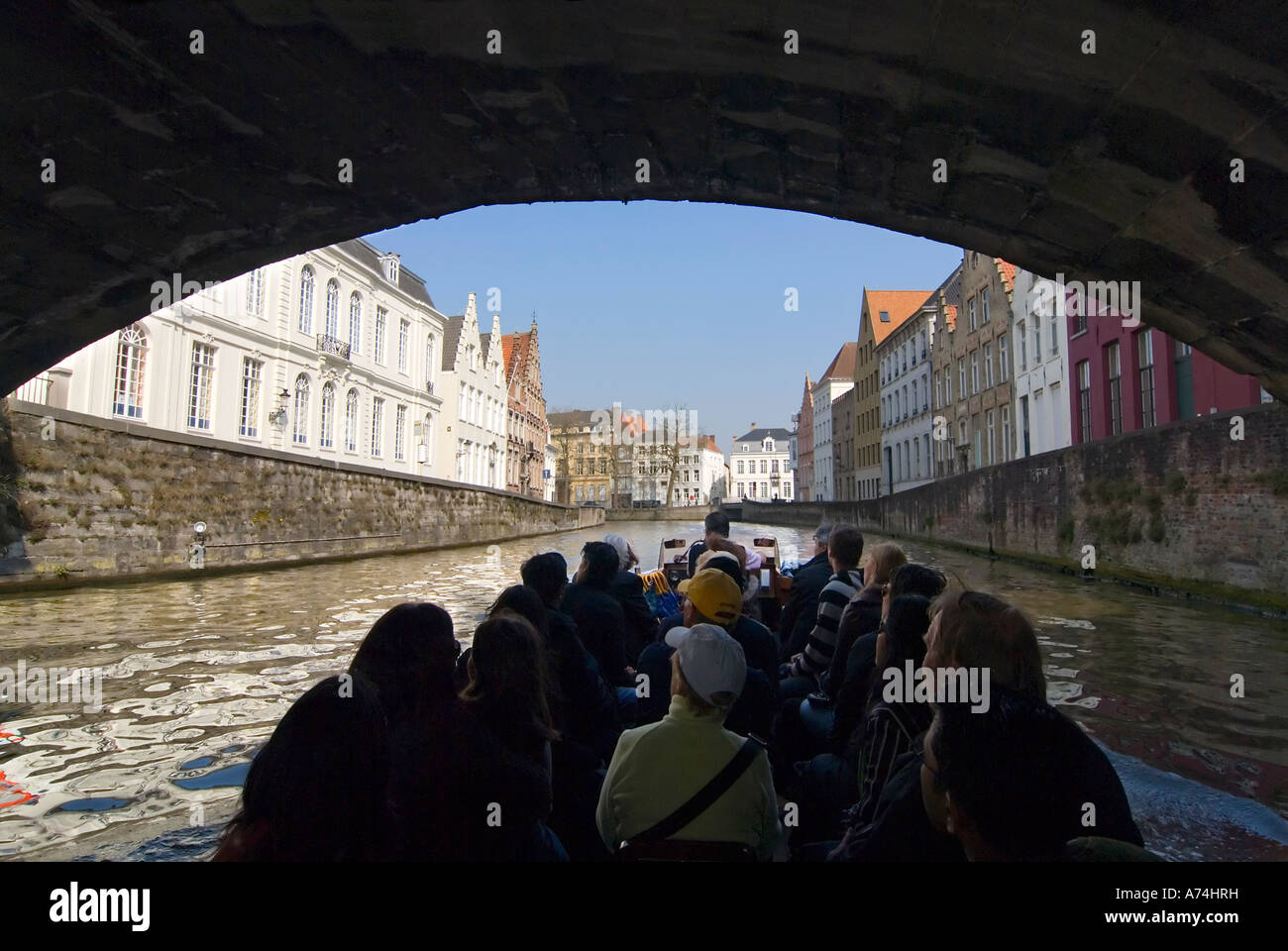 Horizontale Ansicht von Touristen unter einer Brücke auf eine geführte Bootsfahrt durch die Kanäle von Brügge an einem sonnigen Tag Stockfoto