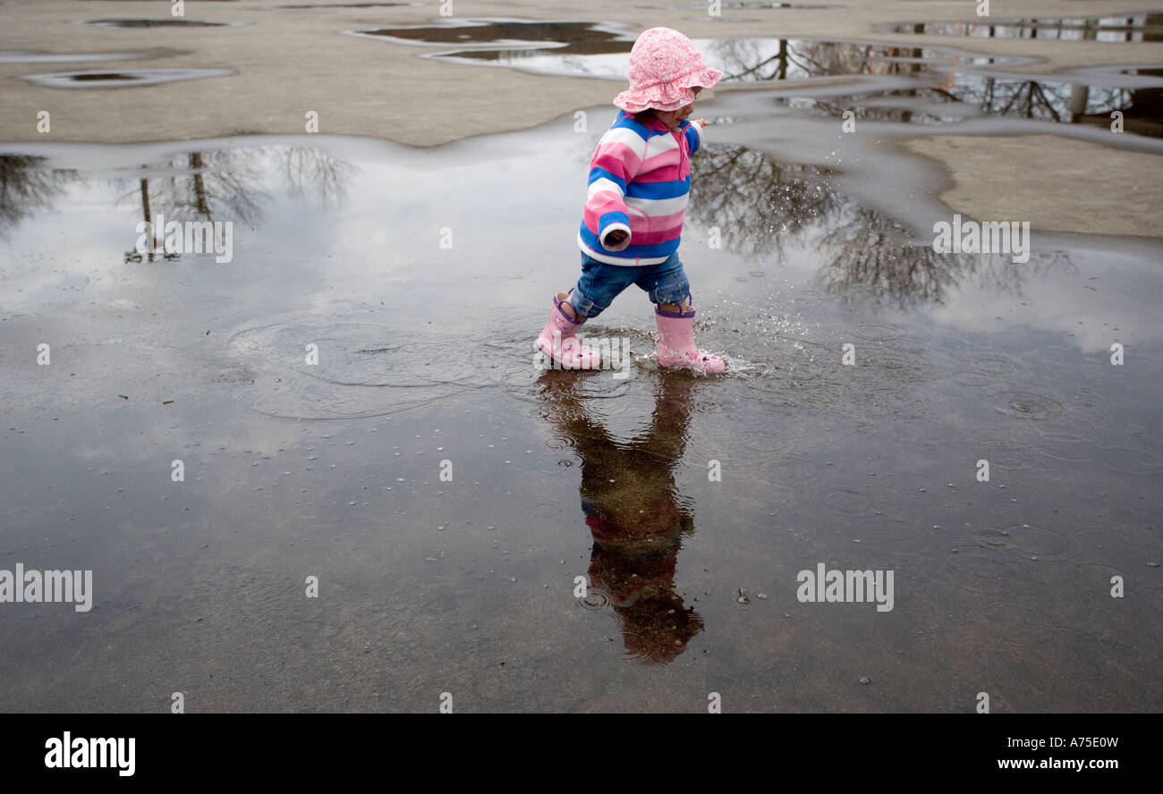 Kind spielt in Pfütze von Regenwasser Stockfoto
