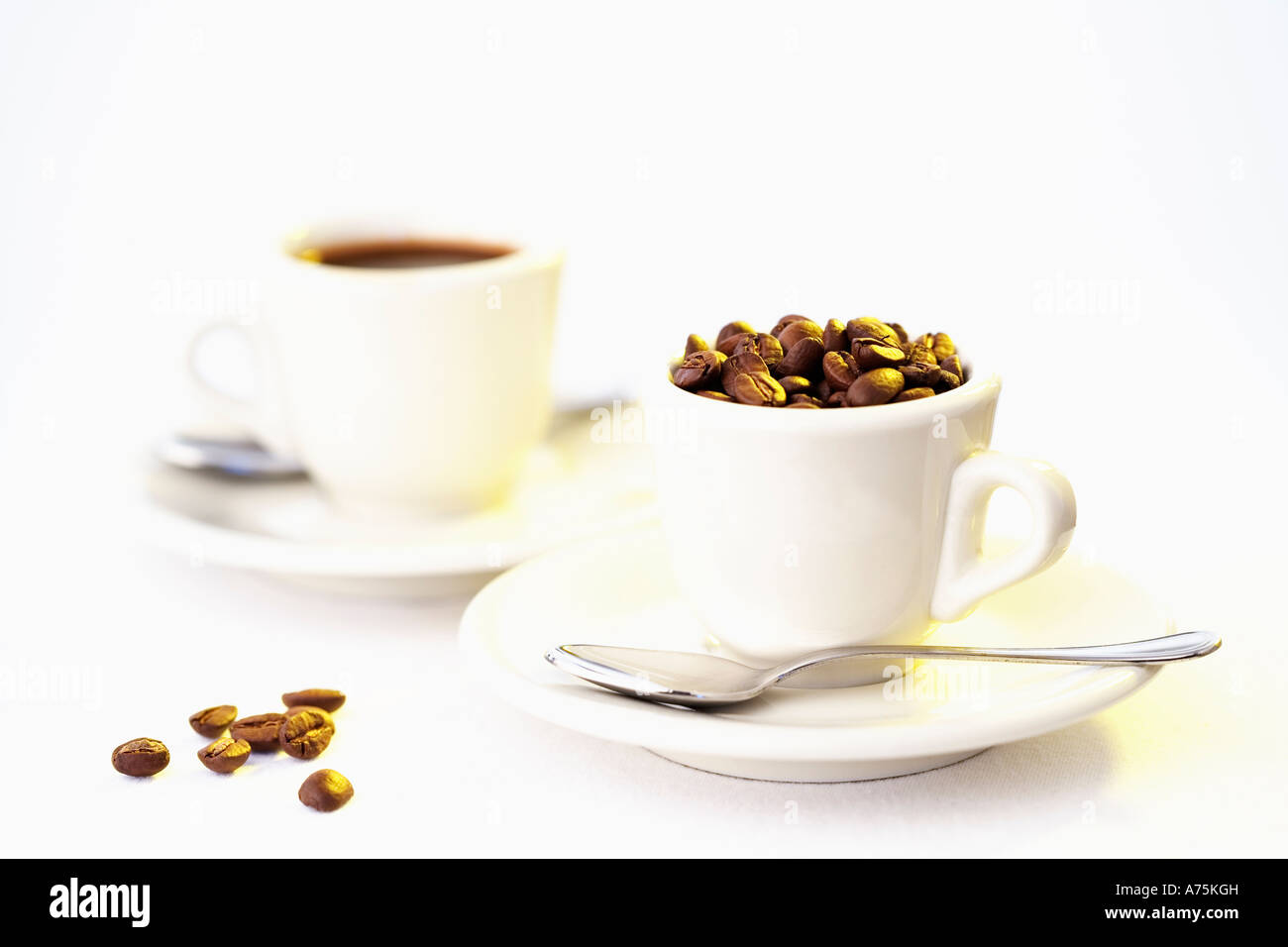 Zwei Espresso-Tassen, die man mit Kaffeebohnen gefüllt weißer Hintergrund Stockfoto