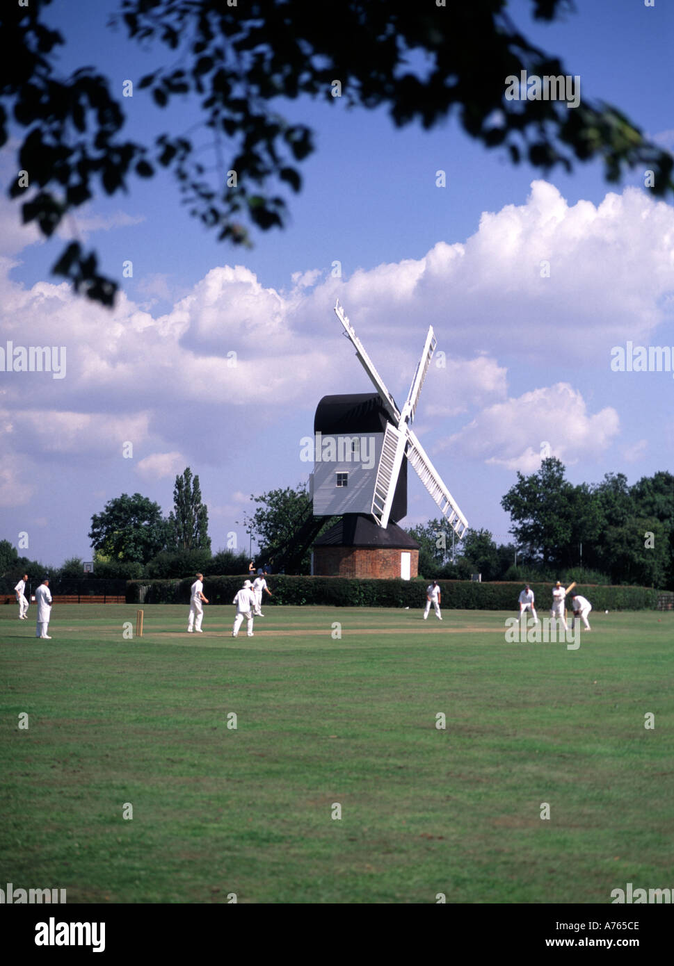 Iconic fundamentale England idyllisches Dorf grün Cricket Match bowler Batsman & Feldspieler Mountnessing Post Mühle Brentwood Landschaft von Essex UK Stockfoto