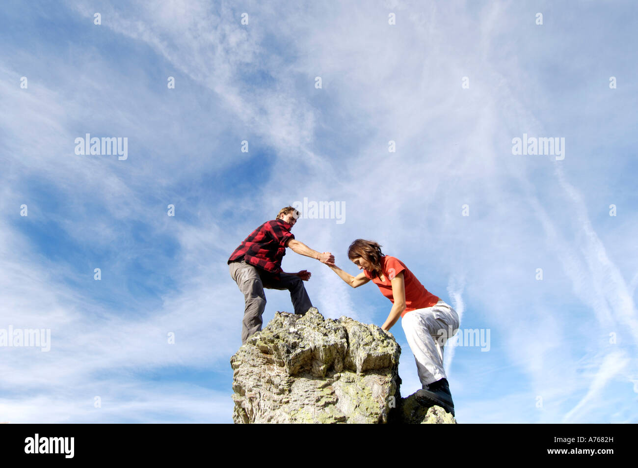 Junges Paar Klettern auf Berggipfel, Mann helfende Frau, niedrigen Winkel anzeigen Stockfoto