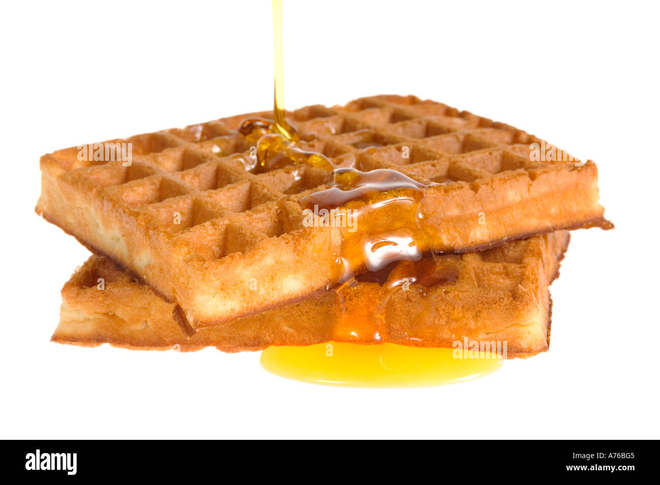 Ahornsirup ausgegossen über zwei heiße Waffeln auf einem reinen weißen Hintergrund. Stockfoto