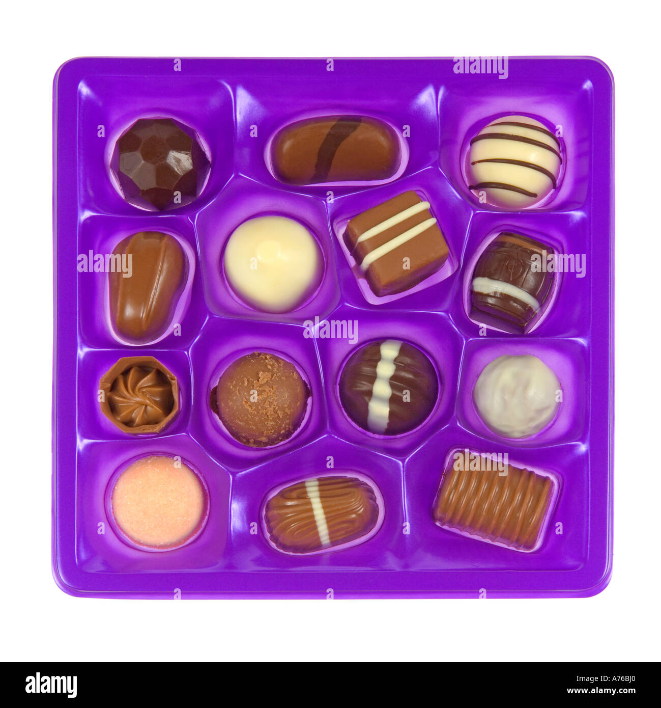 Draufsicht auf eine Auswahl an Pralinen in lila Schale auf einem reinen weißen Hintergrund. Stockfoto