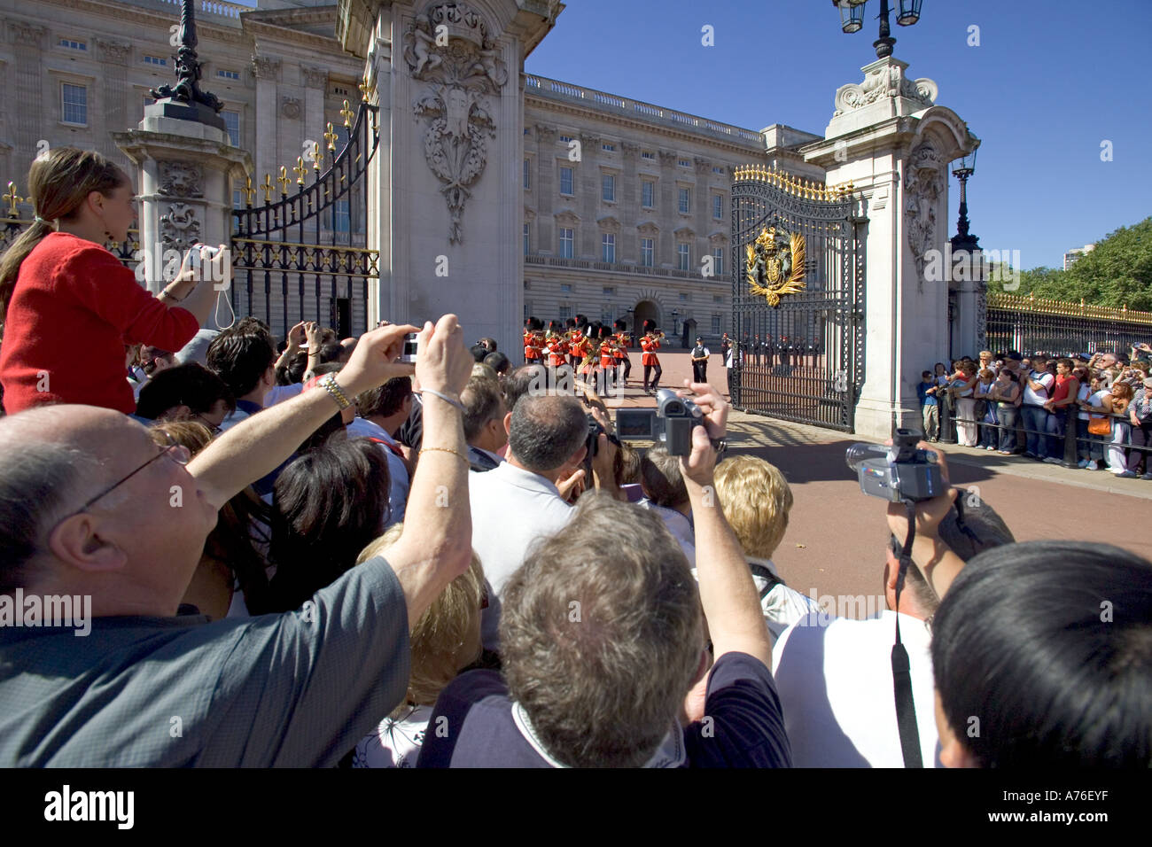 Nahaufnahme von einer Gruppe von Touristen mit den Armen in der Luft zu sehen und fotografieren Sie das Ändern der Guard Parade belasten. Stockfoto