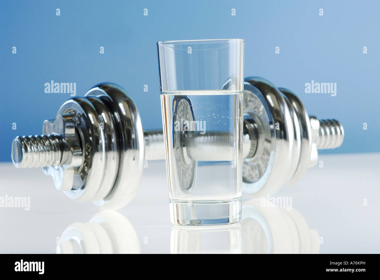 Glas Wasser, Hantel im Hintergrund Stockfoto