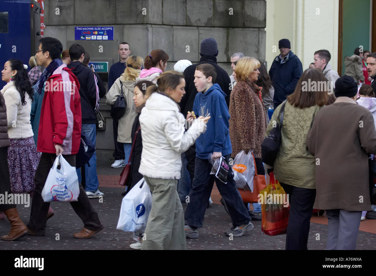 Menschen zu Fuß vorbei an mobile Menschen mit Geldautomaten während Sie Weihnachts-shopping in Belfast Heiligabend Stockfoto