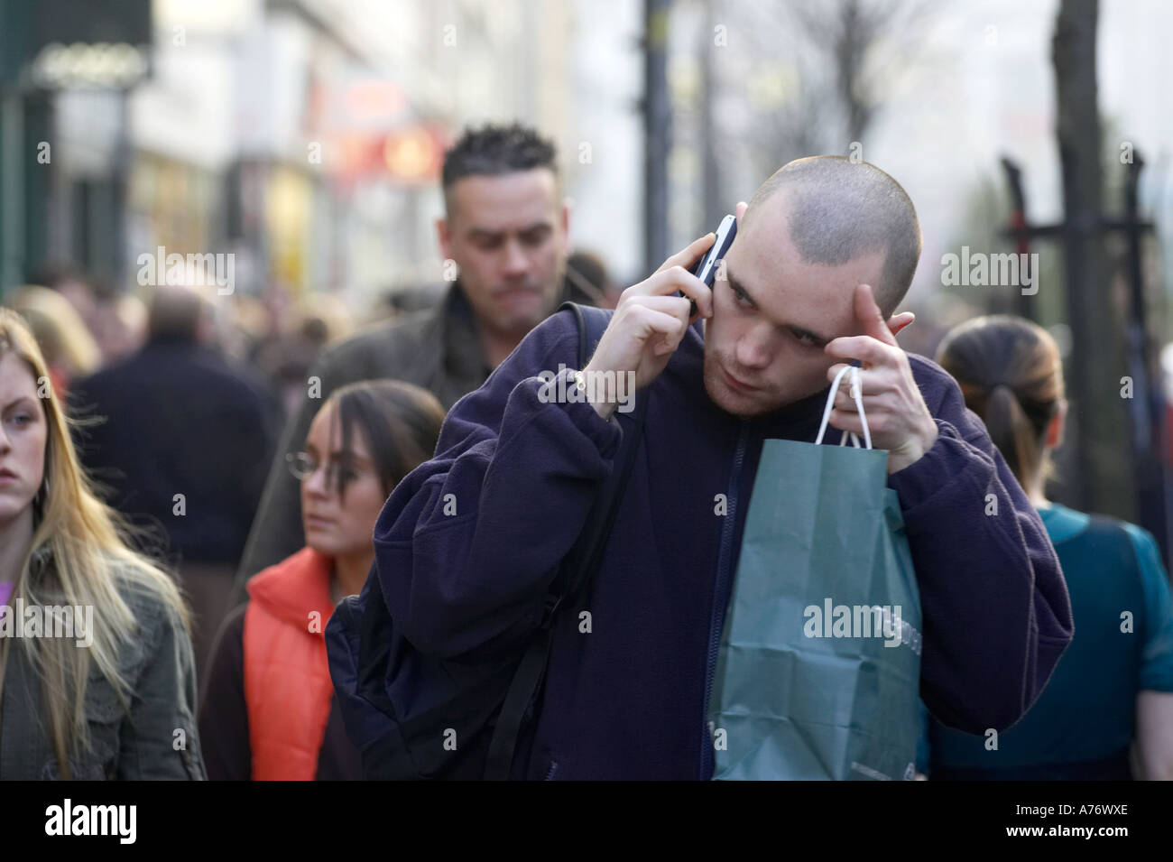 Junge rasierte gingen Mann auf dem Handy in Menge während Weihnachtseinkäufe in Belfast-Heiligabend-Nordirland Stockfoto