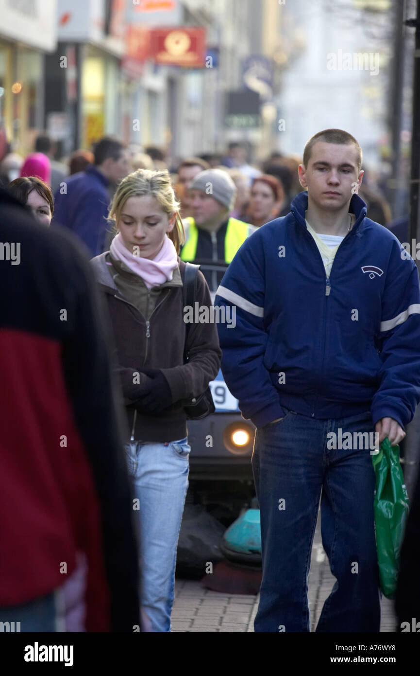 junge Menschen zu Fuß vor der motorisierten Straße Reiniger in Scharen, Weihnachtseinkäufe in Belfast Heiligabend Stockfoto