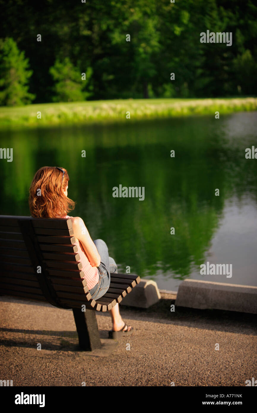 Frau sitzt an einem Teich Stockfoto