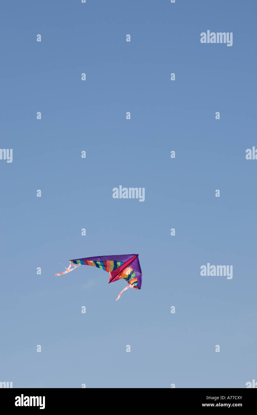 Bunte billige Kunststoff Kinder Spielzeug Drachenfliegen in klaren, blauen wolkenlosen Himmel Stockfoto