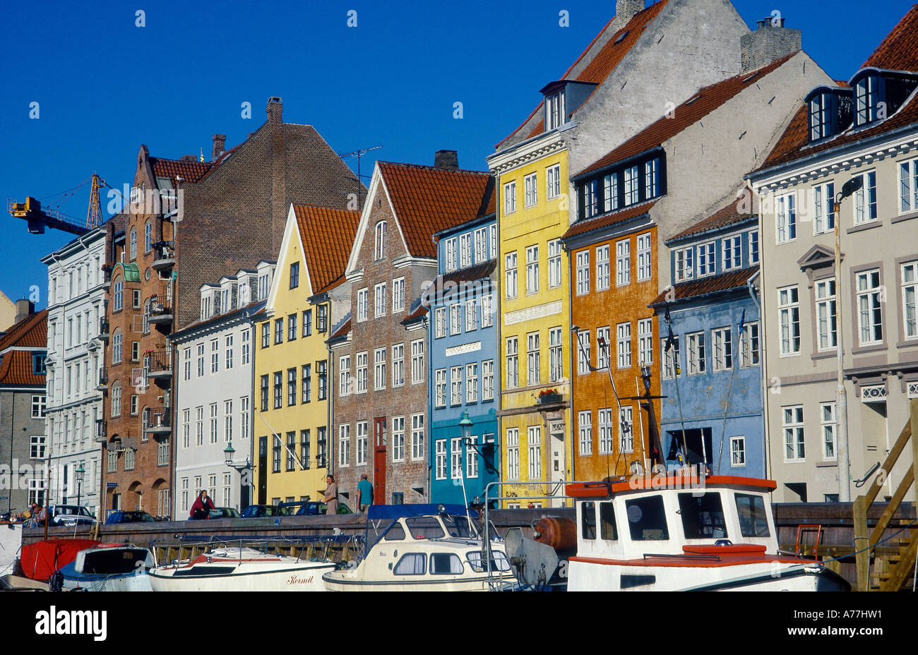Nyhavn Kanal Zeile C18th Housefronts Painted verschiedenfarbig Kran Boote vertäut Menschen am Kai Stockfoto