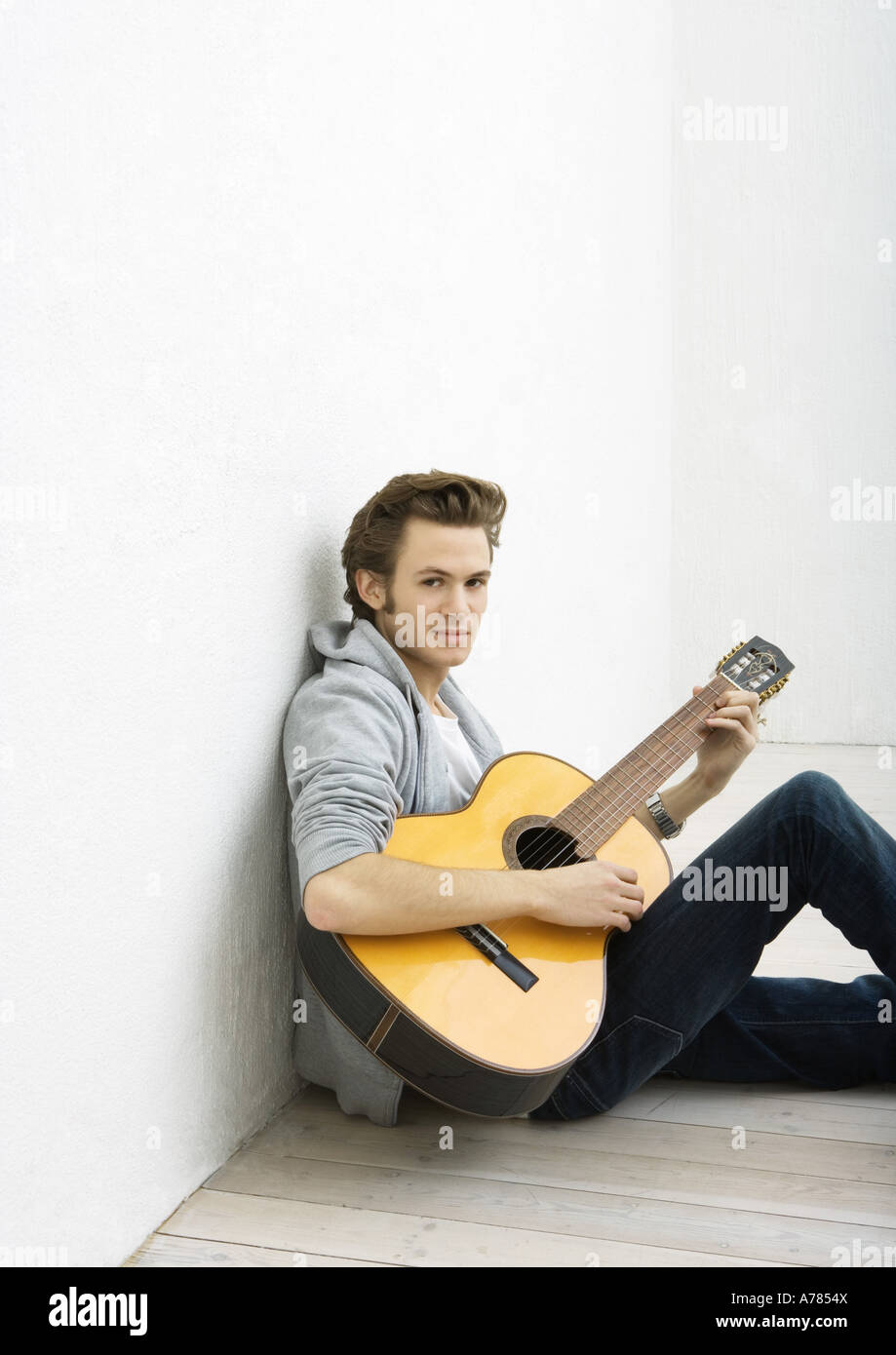 Junger Mann am Boden, Gitarre spielen Stockfoto