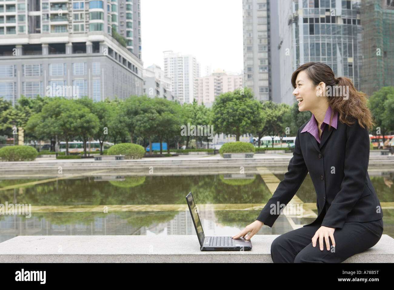 Geschäftsfrau mit Laptop von Wasser im Büropark Stockfoto