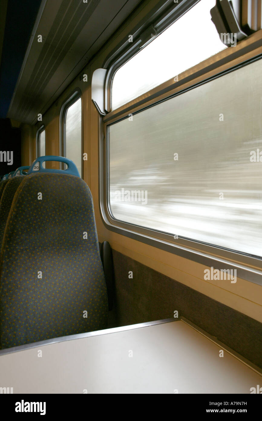 ein Porträt von einem leeren Zug Sitz und Tisch mit der ländlichen Gegend mit Geschwindigkeit im Fenster geleitet Stockfoto