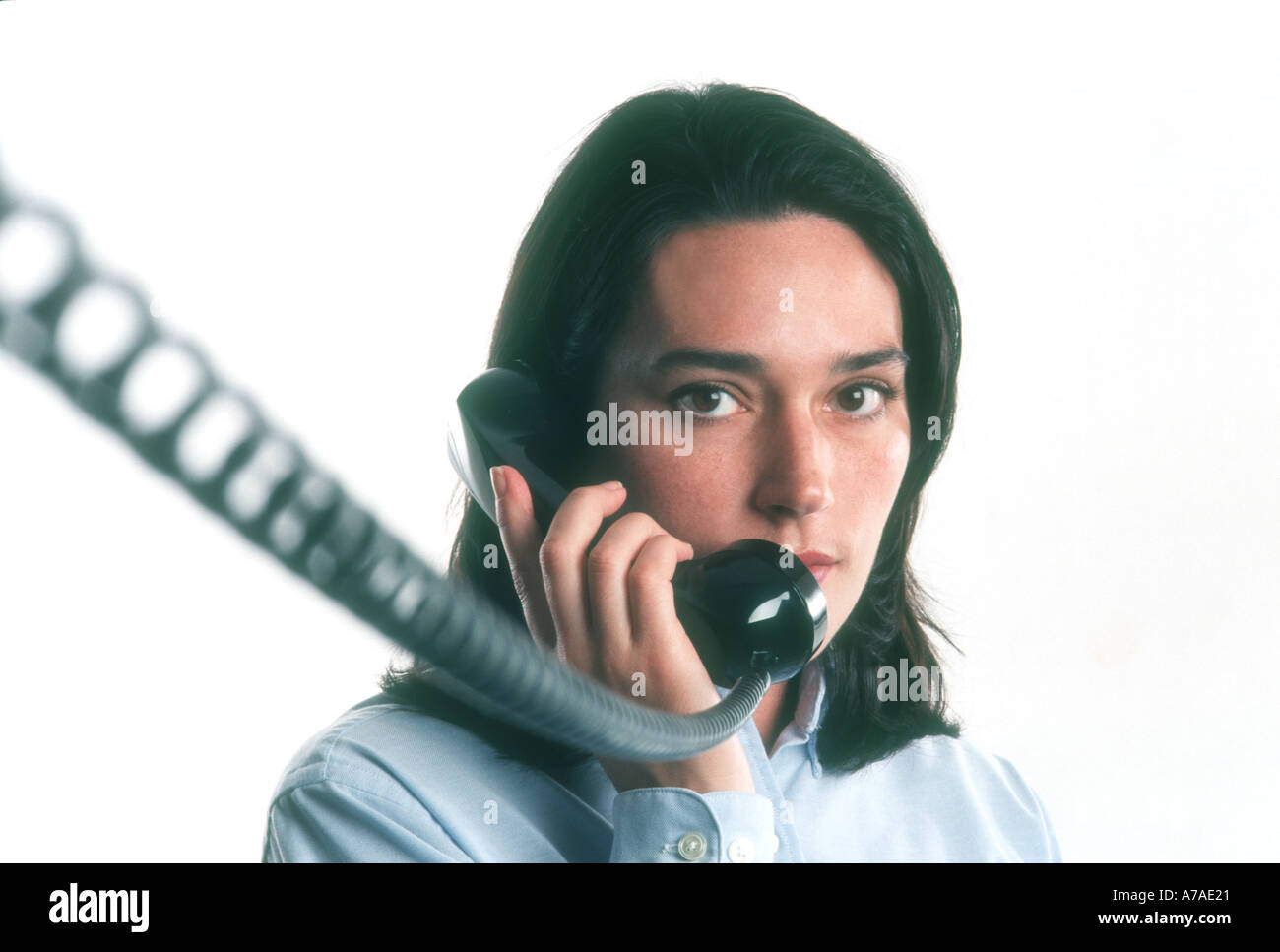 Frau Exekutive auf Handy mit langen Spiralkabel im Büro Stockfoto