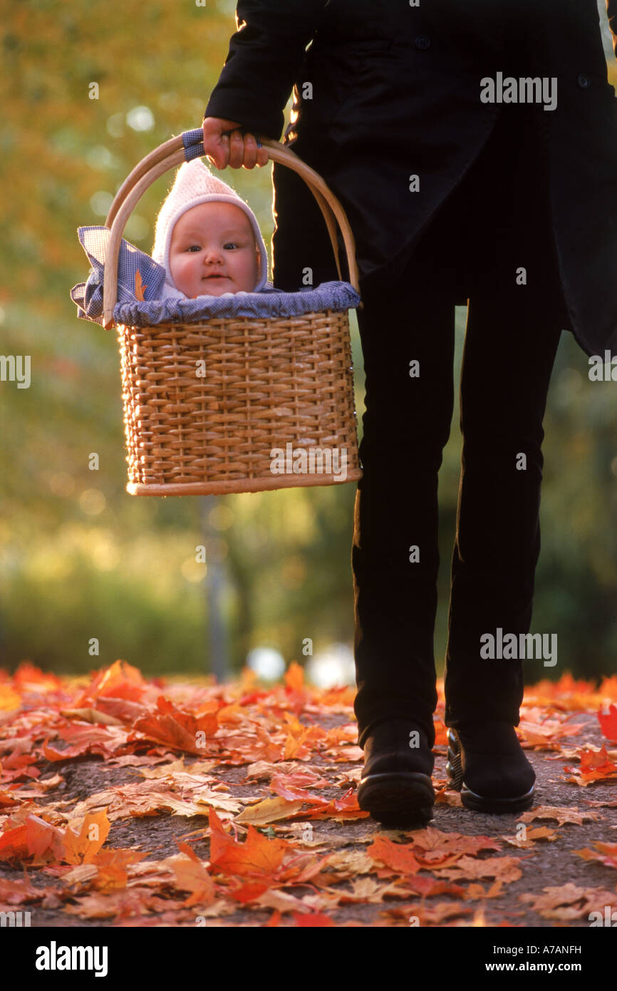 Mutter, nehmen ihr Baby in einem Korb für Spaziergang im Herbst Stockfotografie