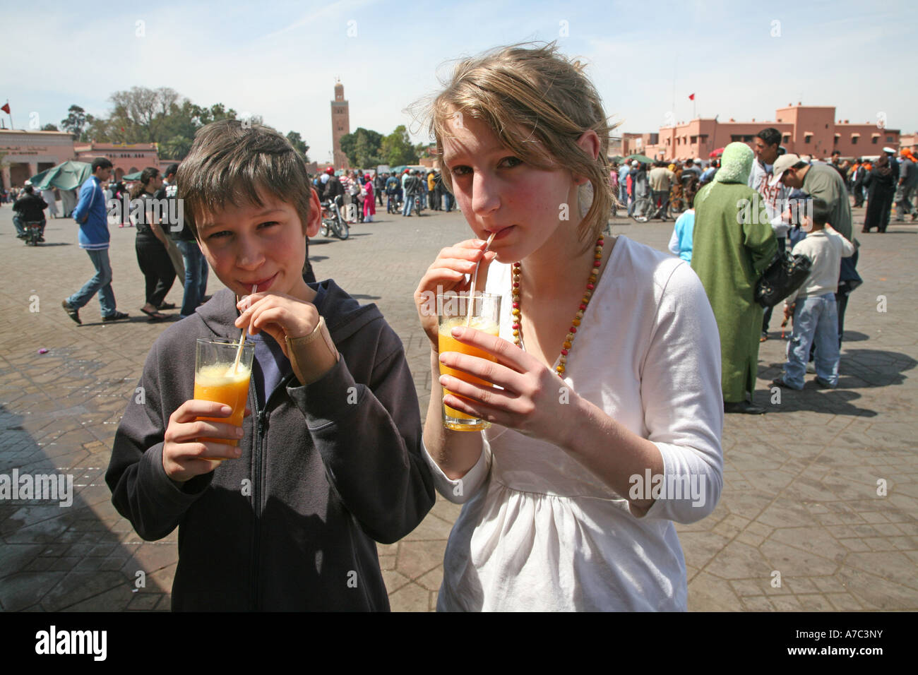 Junge und Mädchen Kinder trinken frischen gepressten Orangensaft mit Strohhalm aus Glas Platz Jema al-Fna, Marrakesch, Marokko Stockfoto