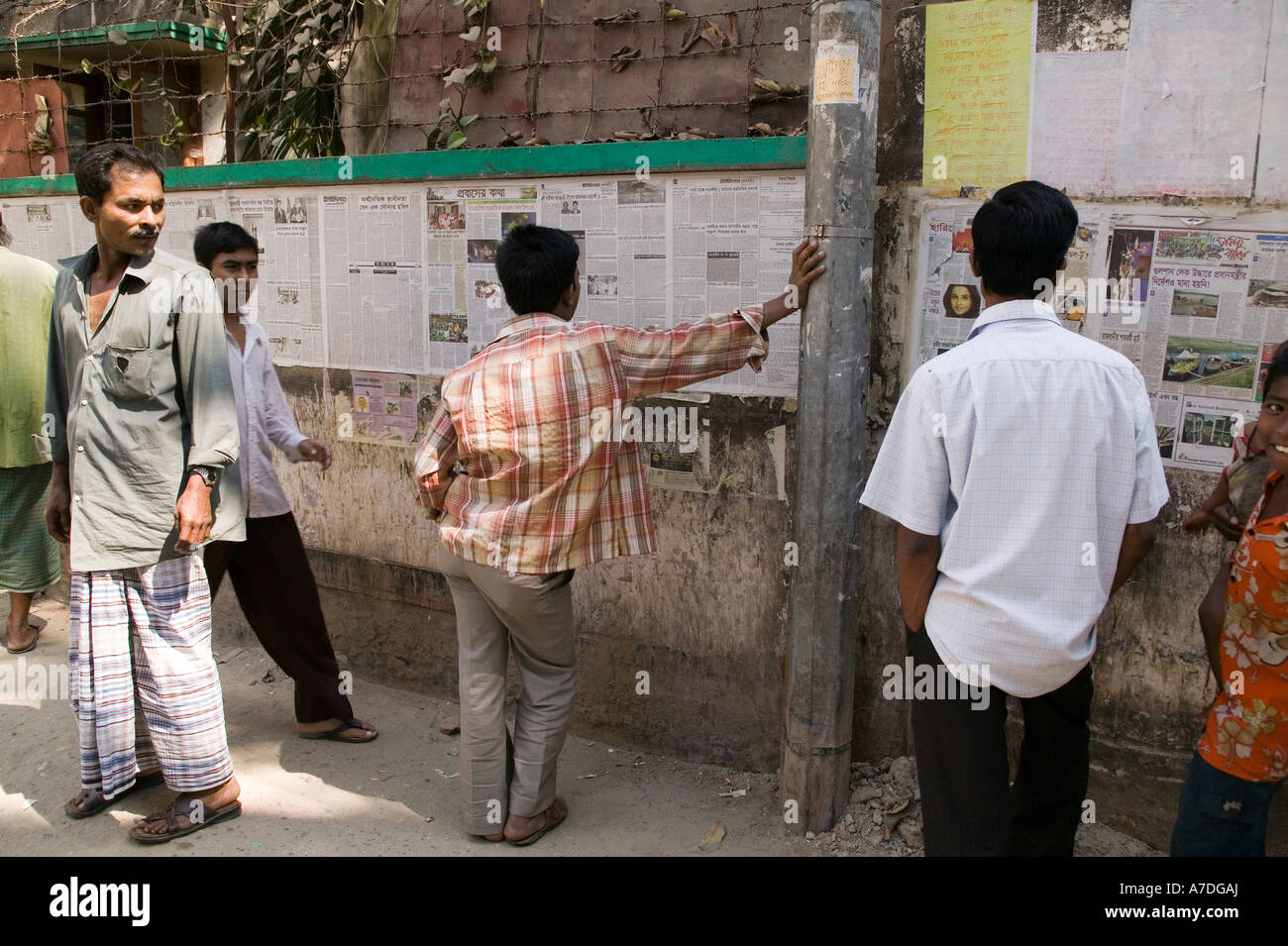 Männer lesen eine Zeitung, die täglich für die Öffentlichkeit zum Lesen kostenlos in Dhaka Bangladesch gebucht wird Stockfoto