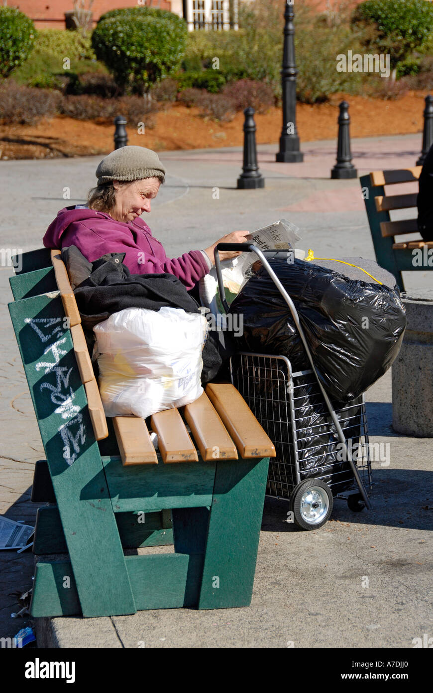 Obdachlose Frau liest die Zeitung auf einer Bank im Stadtteil Atlanta Georgia Underground Stockfoto