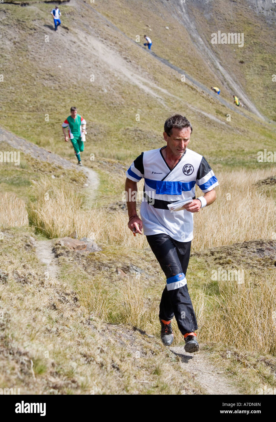 Mann-Orientierungsläufer nach Wanderweg mit anderen Konkurrenten hinter Wales UK Stockfoto