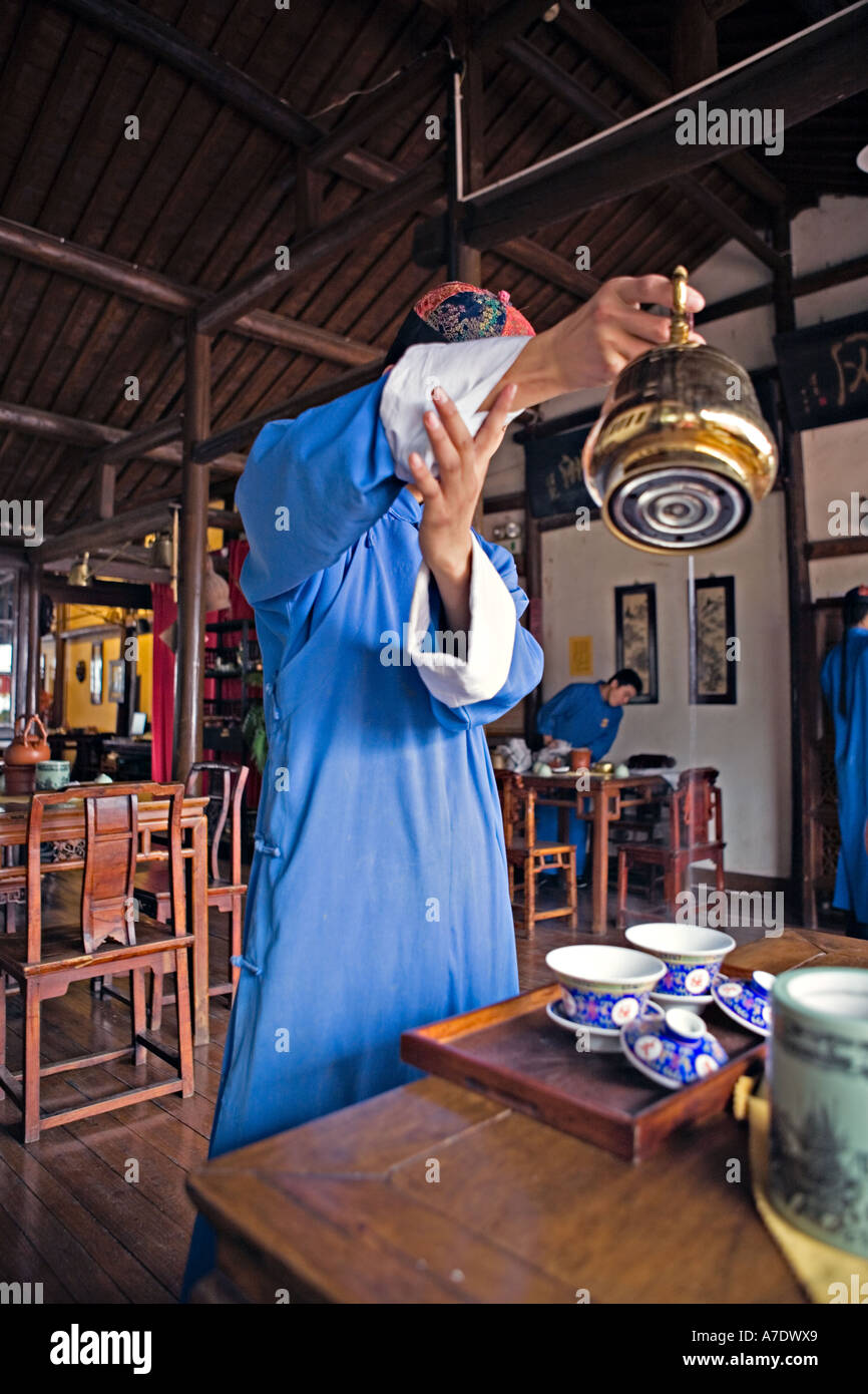 CHINA HANGZHOU Young Teetee Server gießt aus hohen verwenden Messing Teekanne Stockfoto