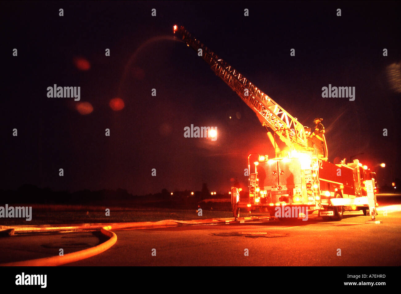 Wisconsin Feuerwehr Besprühen mit Wasser aus einem Leiterwagen in der Nacht Stockfoto