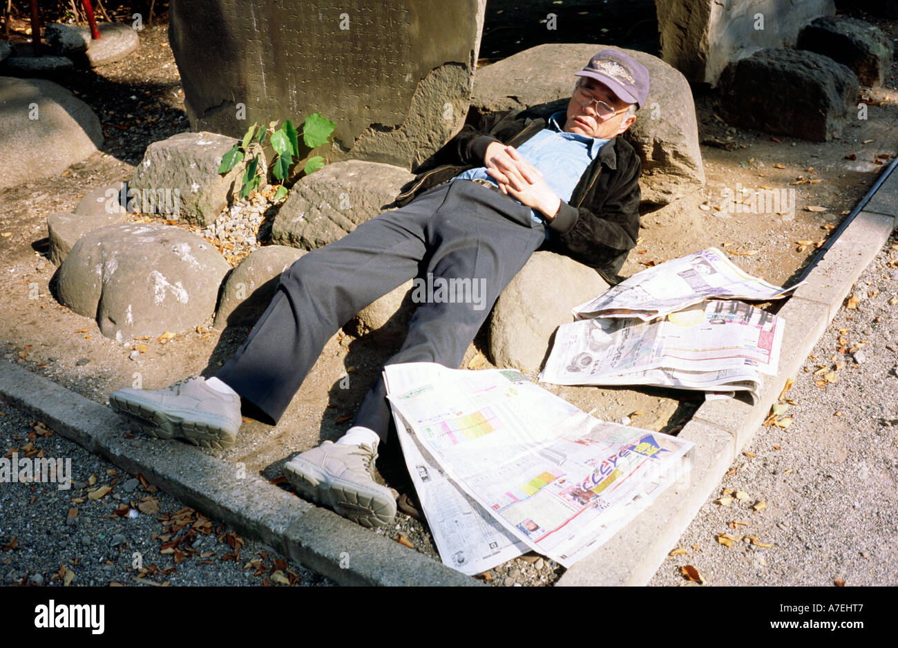 7. November 2004 - Mann schläft oben auf Felsen Anordnung innen Denkmal in Asakusa in der japanischen Hauptstadt Tokio. Stockfoto