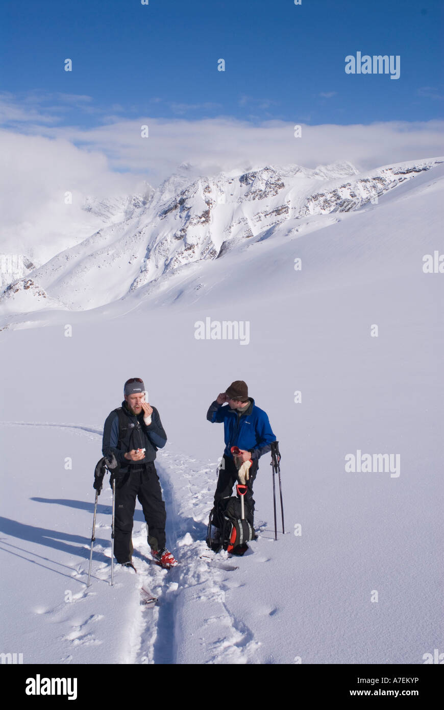 Zwei Skifahrer, die Anwendung von Sonnenschutzmitteln während der Häutung oben die Asulkan Gletscher, Rogers Pass, Selkirk Mountains, kanadischen Rocky Mountains, Kanada Stockfoto