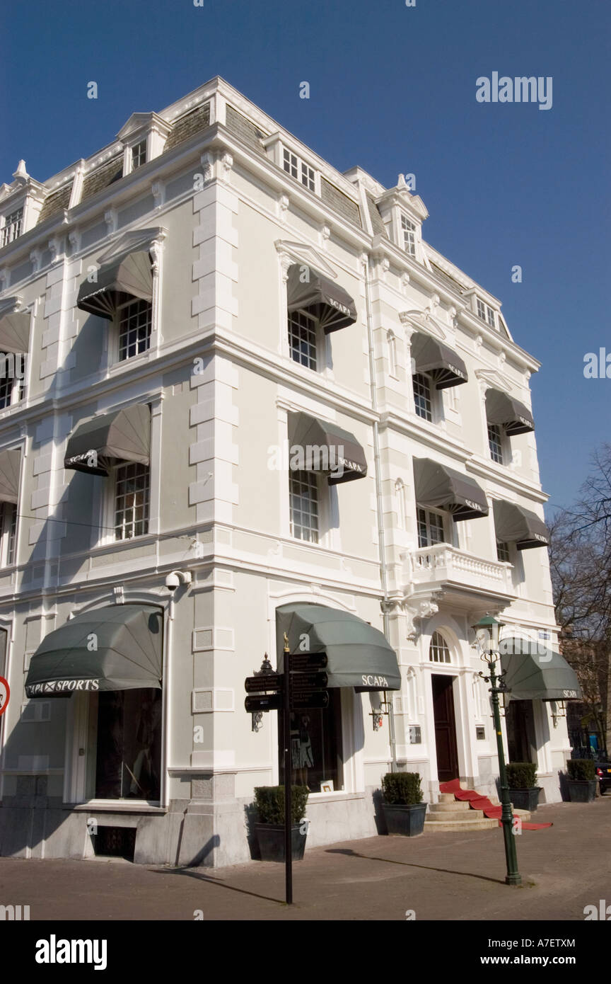 Weißes Gebäude des Scapa Sport Fashion House in den Haag, den Haag, Holland. Klassische Architektur mit grauen Markisen und rotem Teppicheingang. Stockfoto