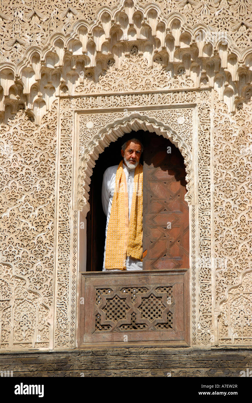 Mann trägt traditionelle Tuch sieht aus dem Fenster, verziert mit reichen Ornamenten Medersa Bou Inania Fes El-Bali-Marokko Stockfoto