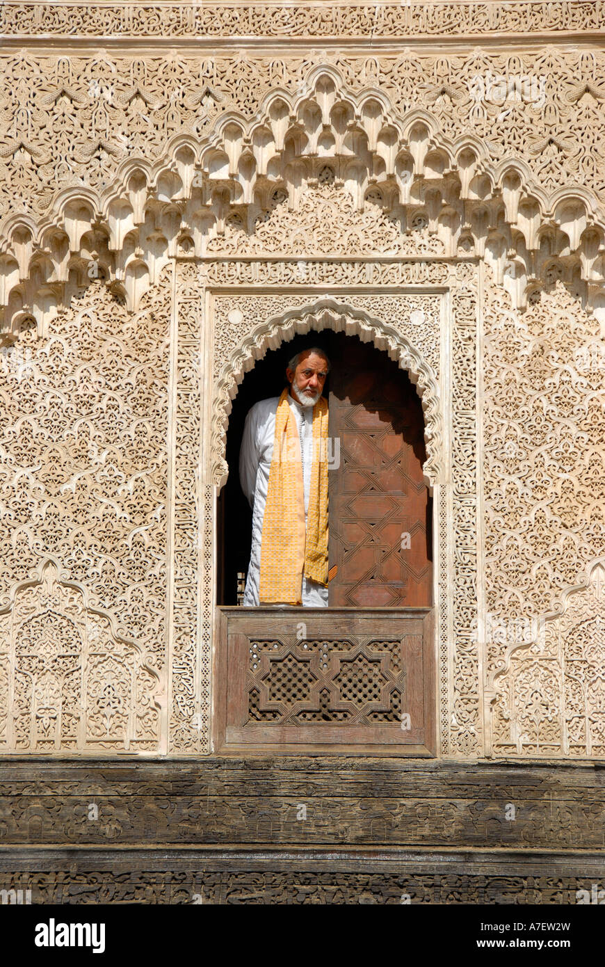 Mann trägt traditionelle Tuch sieht aus dem Fenster, verziert mit reichen Ornamenten Medersa Bou Inania Fes El-Bali-Marokko Stockfoto