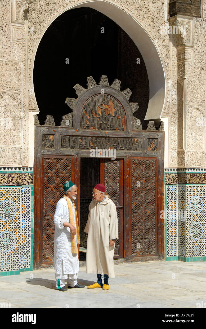 Männer tragen traditionelle Tuch stellen Sie sich vor ein altes reich geschnitzte hölzerne Tor sprechen Medersa Bou Inania Fes El-Bali Marokko Stockfoto