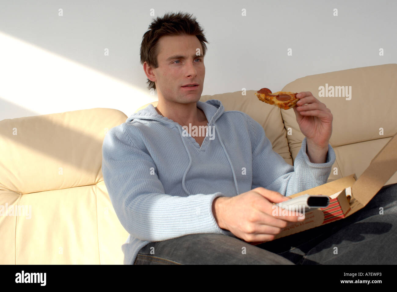 Mann sitzt auf einem Sofa Pizza essen und Fernsehen Stockfoto