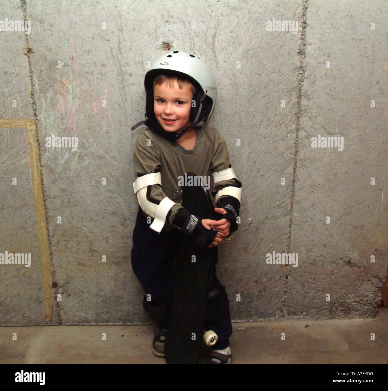 Fünf Jahre alten Jungen Posen mit Skateboard Sicherheitsausrüstung tragen Stockfoto