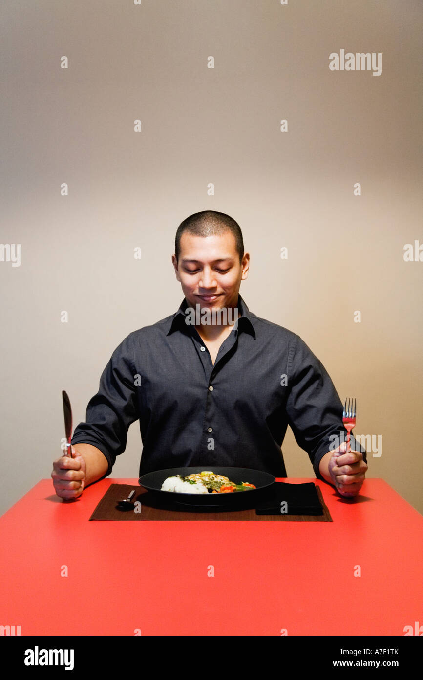 Asiatischer Mann am Tisch mit vollen Teller mit Essen Stockfoto