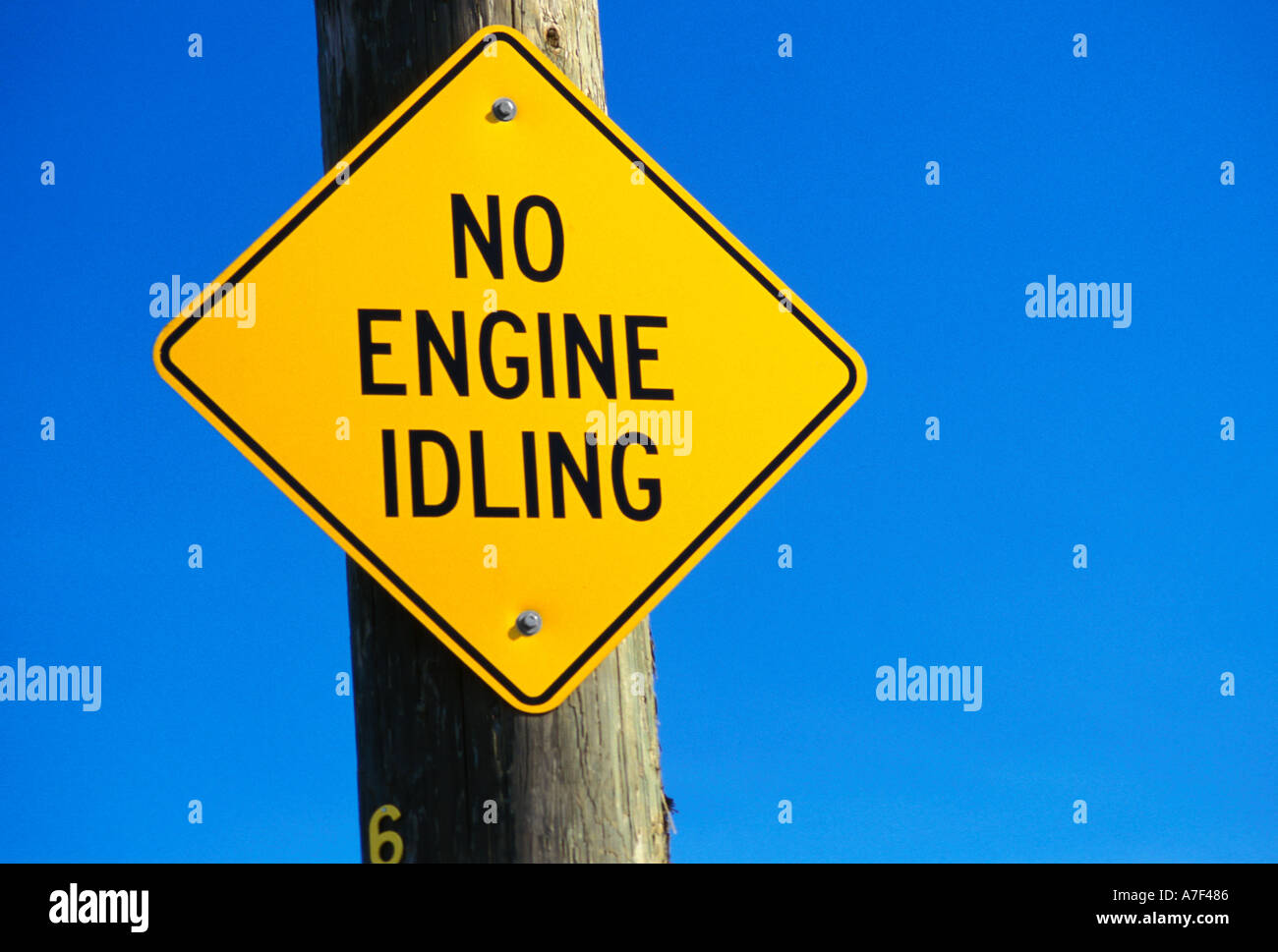 Kein Motor im Leerlauf Rauten gelbes Straßenschild oder Verkehrszeichen auf ein Strommast mit einem klaren blauen Himmelshintergrund Stockfoto