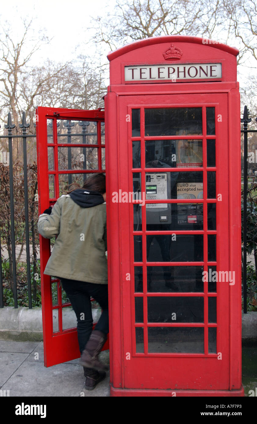 Ein junges Mädchen in einer roten Londoner Telefonzelle Stockfoto