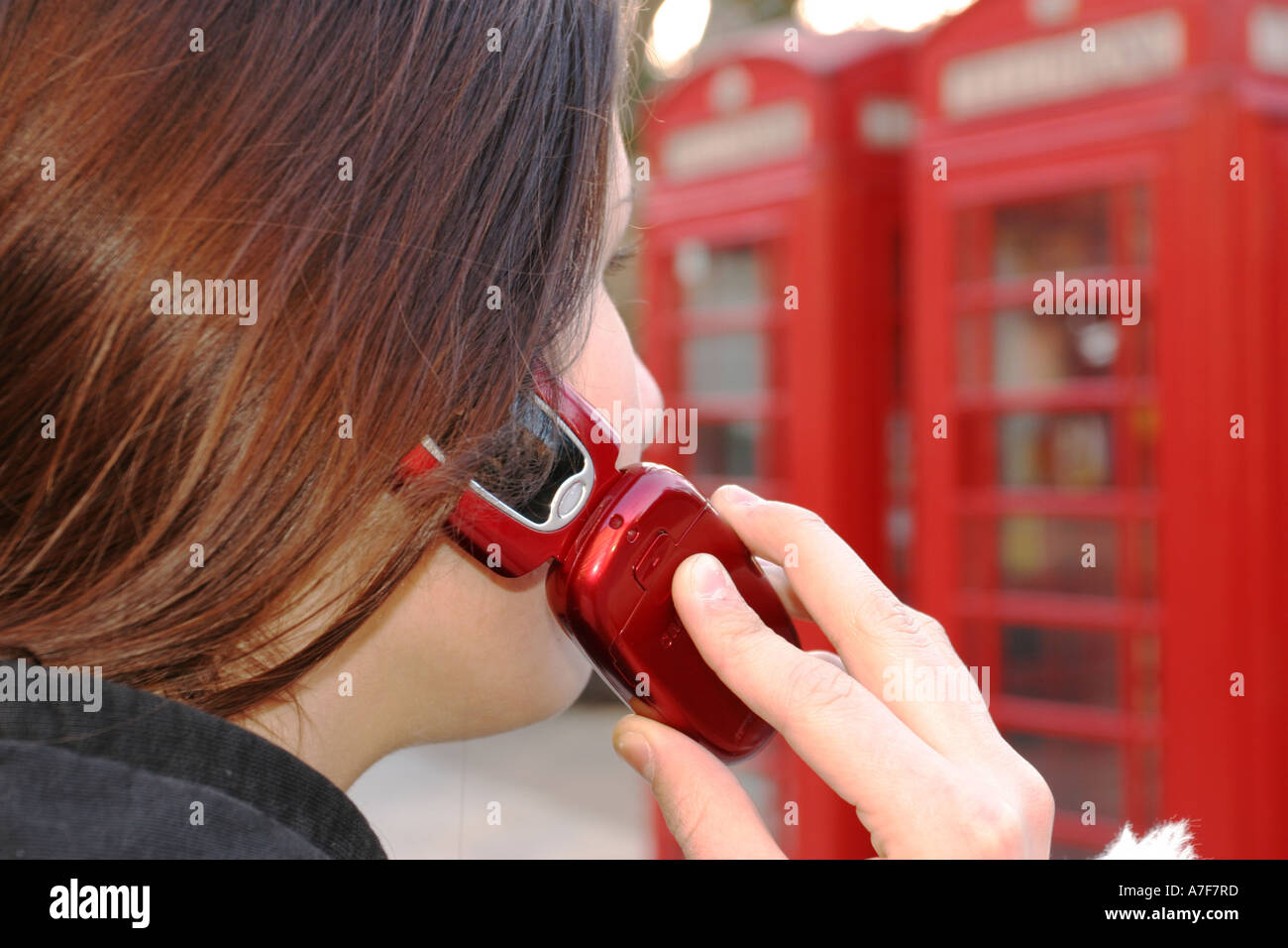 Mädchen mit einem roten Handy mit ein paar roten Londoner Telefonzellen Stockfoto
